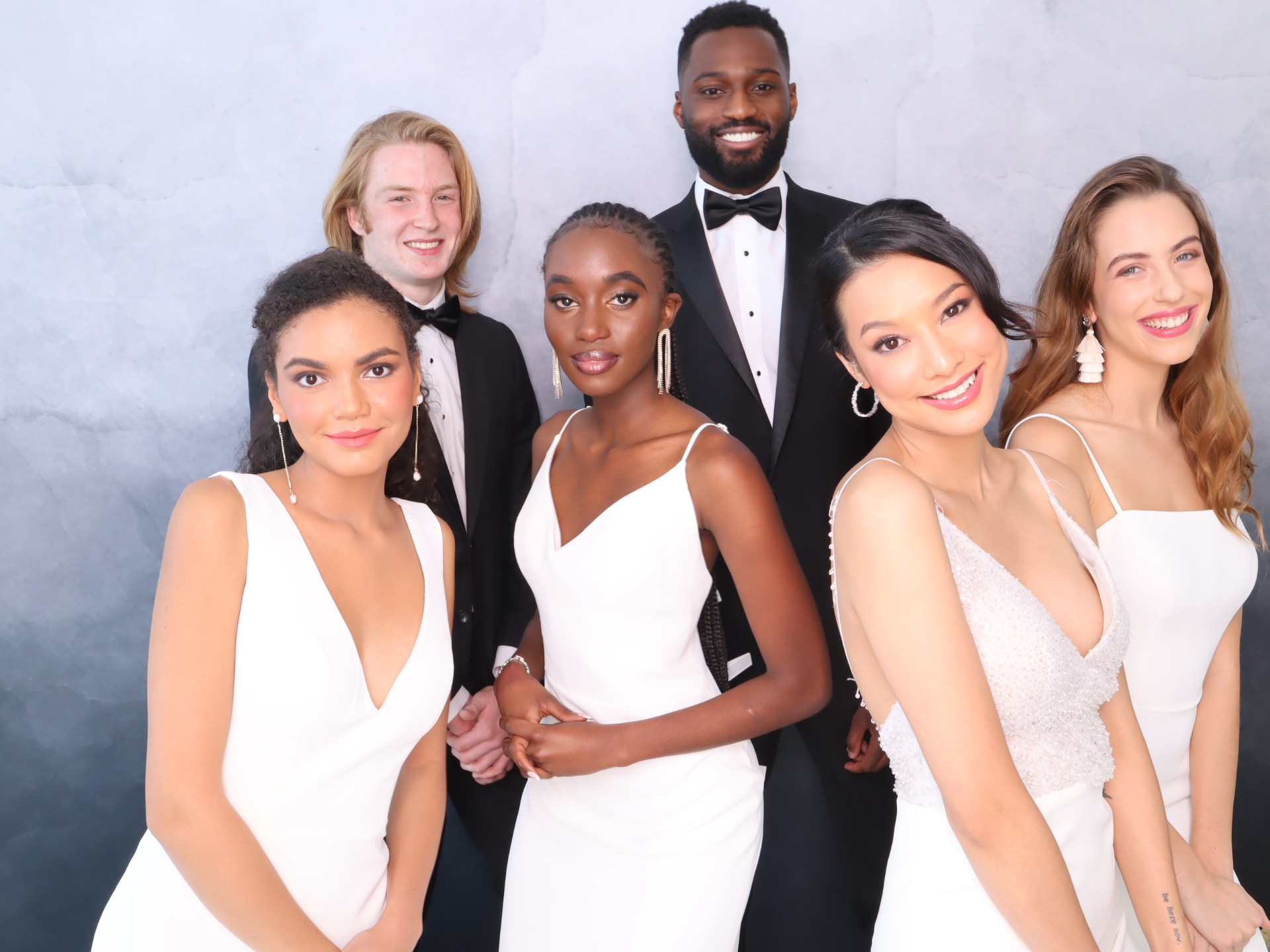 Group of friends in formalwear smiling together in a studio photo booth