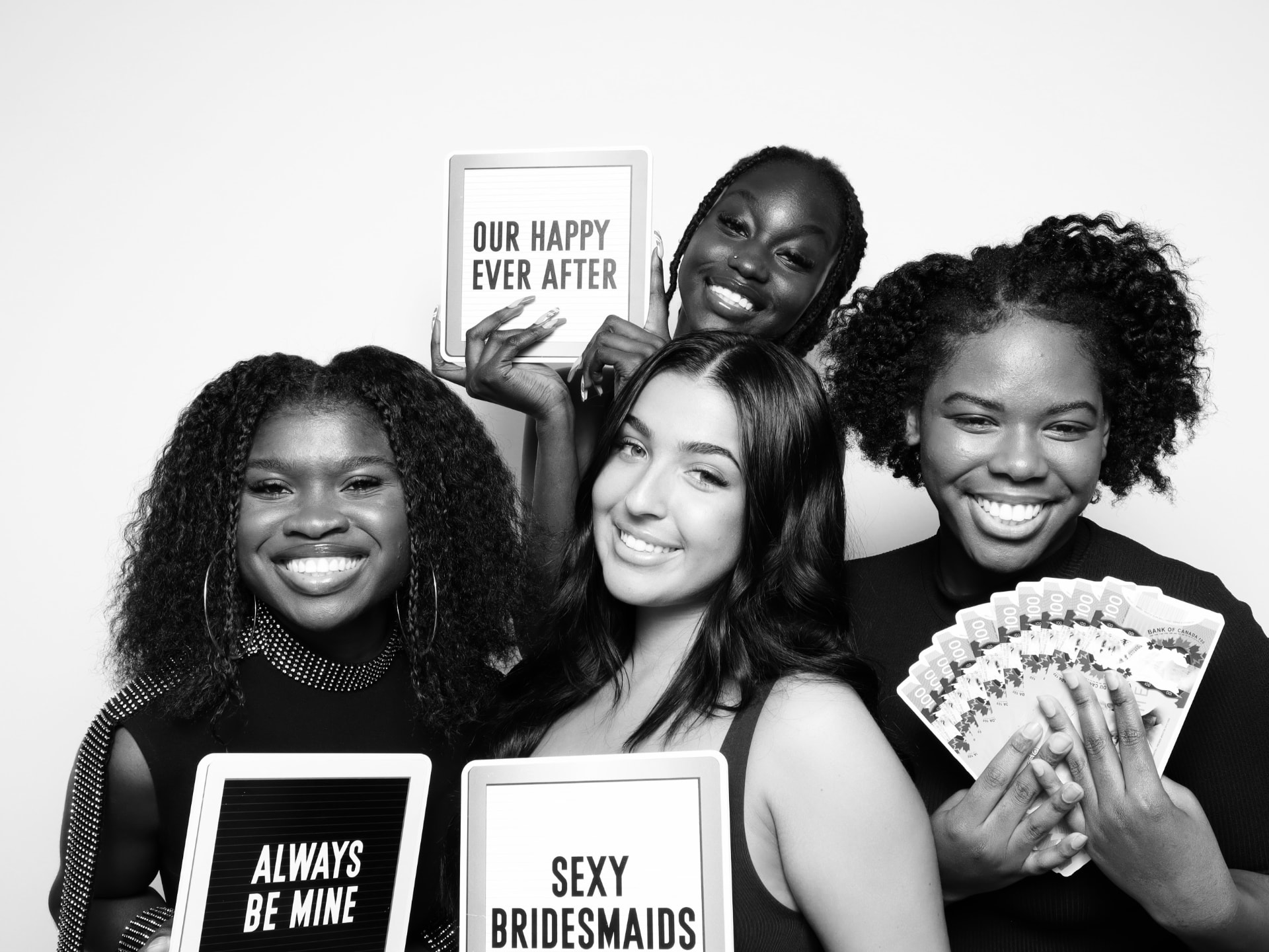 Bridesmaids laughing with letter board signs in a black and white photo booth portrait
