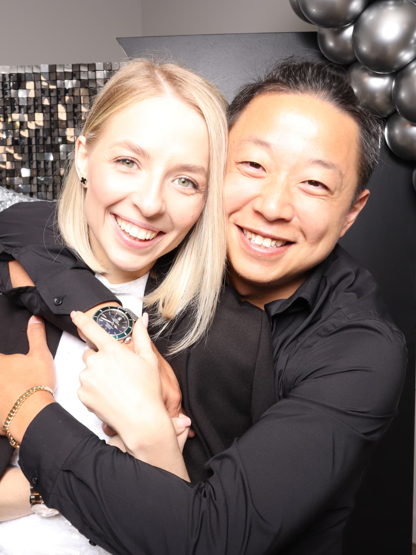 A couple embracing in front of a black sequin photo booth backdrop
