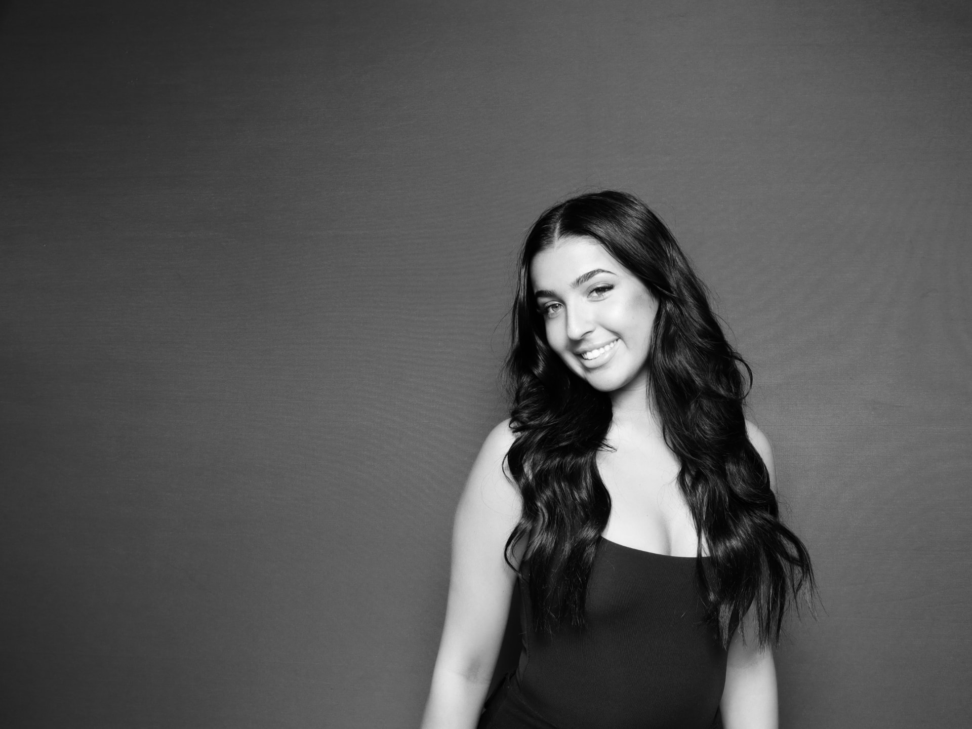 Black and white studio portrait of a guest smiling in a photo booth